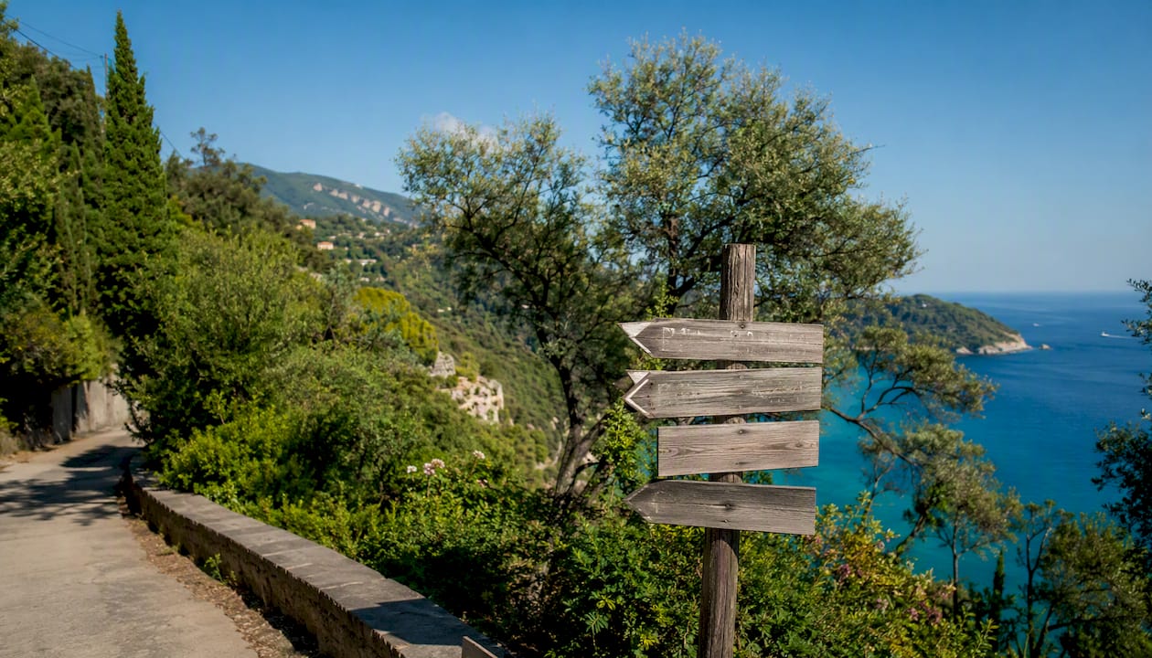 Strada panoramica che costeggia le rocce e cartello in legno sull’Isola d’Elba