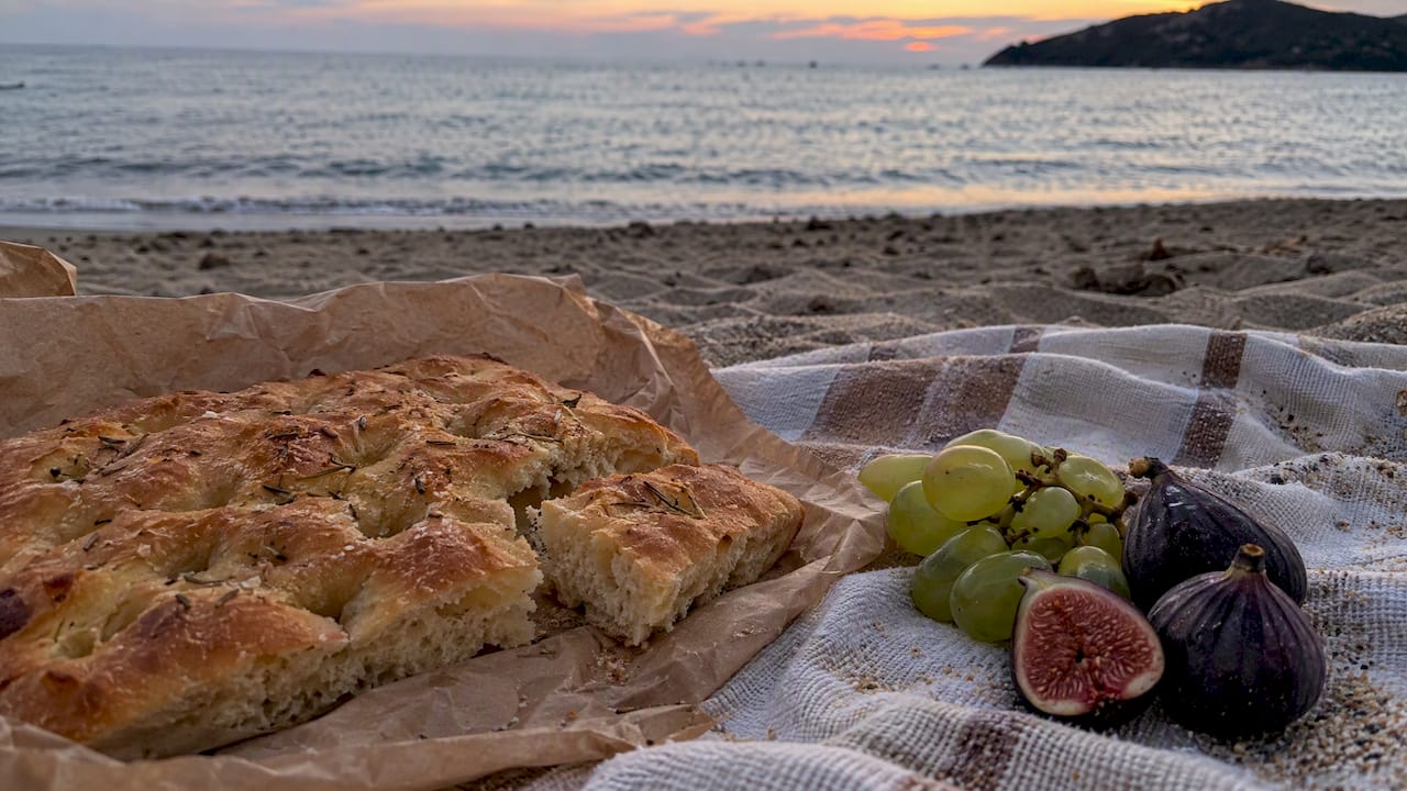 Focaccia e frutta sulla spiaggia al calar del sole